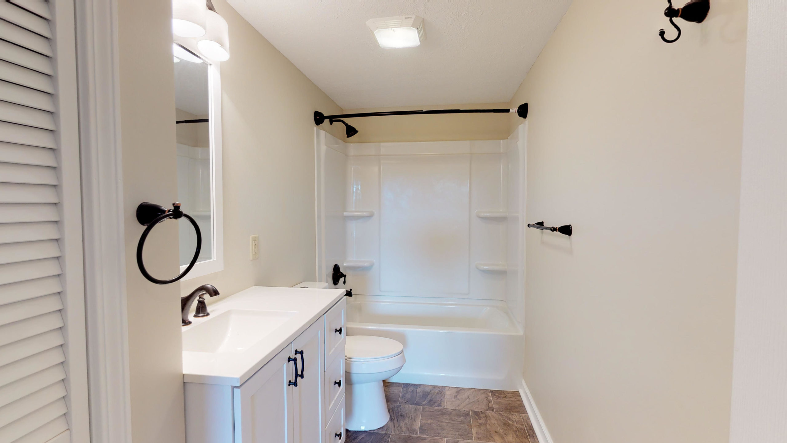 Modernized bathroom with a white double-drawer vanity, dark hardware, and a clean white tub-and-shower enclosure.