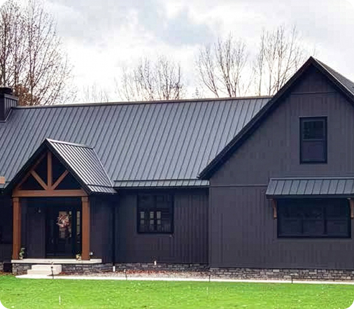 Modern dark gray farmhouse with a black metal roof and natural wood porch accents, representing a completed renovation.