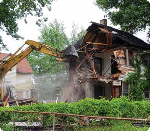 A yellow excavator demolishing an old, two-story house to clear land for new Portage County development.