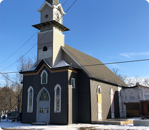 Historic church with gray siding and Gothic windows under renovation, serving as an investment property example.